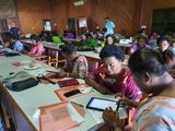 A group of women are in a building undertaking training on tablets to prepare them to take part in a mass drug administration. 